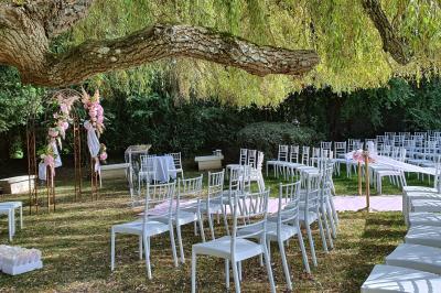 Couronne de fleurs blanches et roses suspendue à un arbre sous la lumière du soleil dans un jardin verdoyant.