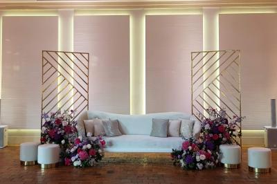 Couronne de fleurs blanches et roses suspendue à un arbre sous la lumière du soleil dans un jardin verdoyant.