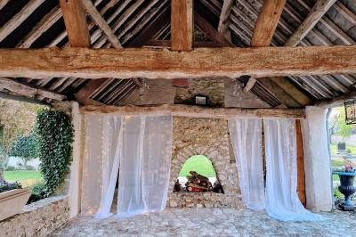 Couronne de fleurs blanches et roses suspendue à un arbre sous la lumière du soleil dans un jardin verdoyant.