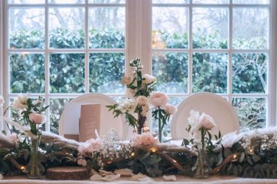 Couronne de fleurs blanches et roses suspendue à un arbre sous la lumière du soleil dans un jardin verdoyant.