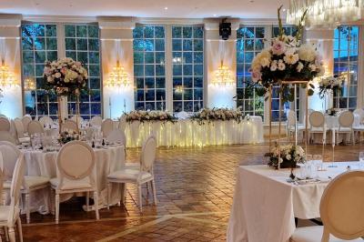 Couronne de fleurs blanches et roses suspendue à un arbre sous la lumière du soleil dans un jardin verdoyant.