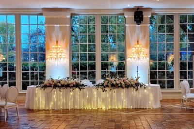 Couronne de fleurs blanches et roses suspendue à un arbre sous la lumière du soleil dans un jardin verdoyant.