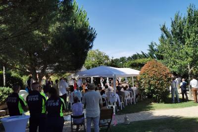 Stand décoratif avec des bonbons dans un parc, entouré d'arbres, de personnes assises et d'enfants jouant.