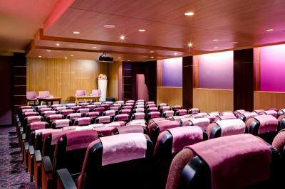 Bibliothèque avec étagères remplies de livres colorés, deux fauteuils jaunes et une table basse avec des livres ouverts.