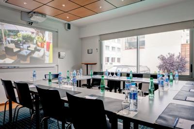 Bibliothèque avec étagères remplies de livres colorés, deux fauteuils jaunes et une table basse avec des livres ouverts.