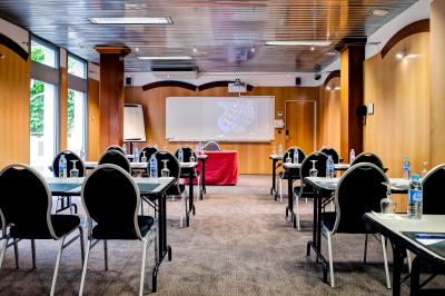 Bibliothèque avec étagères remplies de livres colorés, deux fauteuils jaunes et une table basse avec des livres ouverts.