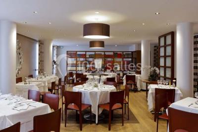 Bibliothèque avec étagères remplies de livres colorés, deux fauteuils jaunes et une table basse avec des livres ouverts.