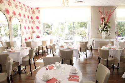 Bibliothèque avec étagères remplies de livres colorés, deux fauteuils jaunes et une table basse avec des livres ouverts.
