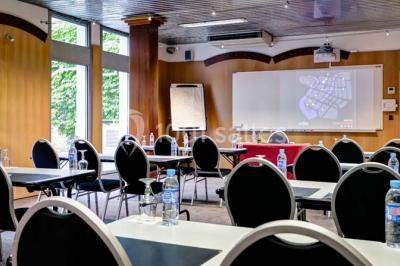 Bibliothèque avec étagères remplies de livres colorés, deux fauteuils jaunes et une table basse avec des livres ouverts.