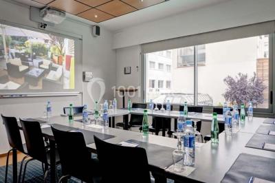 Bibliothèque avec étagères remplies de livres colorés, deux fauteuils jaunes et une table basse avec des livres ouverts.