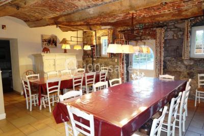 Chambre lumineuse avec deux lits simples, armoire ancienne, murs en bois et fenêtres donnant sur un jardin.