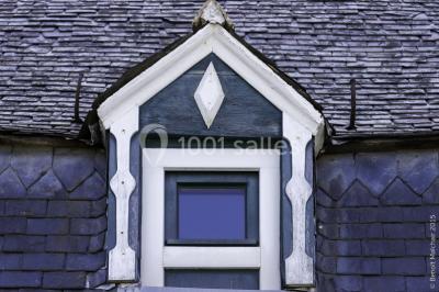 Chambre lumineuse avec deux lits simples, armoire ancienne, murs en bois et fenêtres donnant sur un jardin.