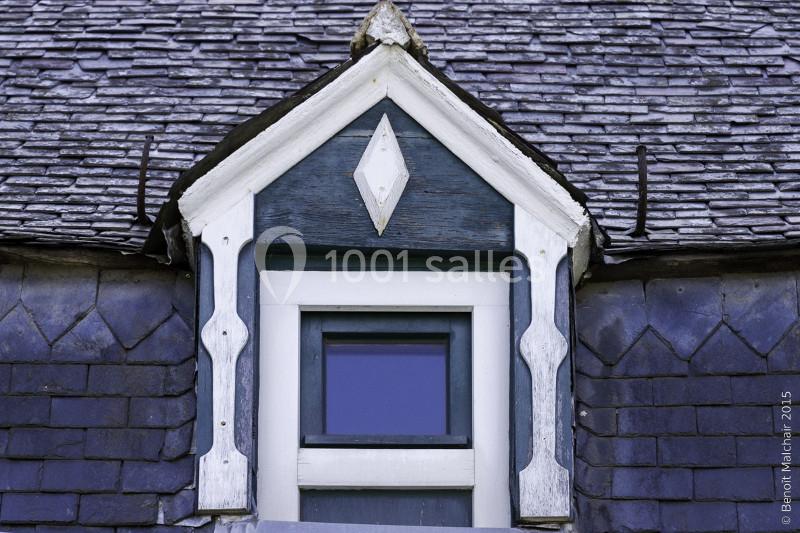 Fenêtre mansardée entourée de bois peint en bleu et blanc, intégrée à un toit en ardoise.