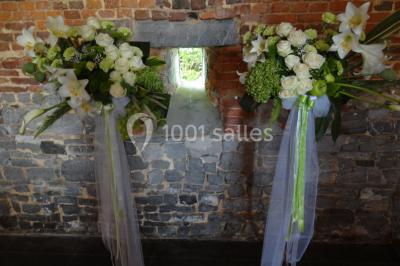 Chambre lumineuse avec deux lits simples, armoire ancienne, murs en bois et fenêtres donnant sur un jardin.