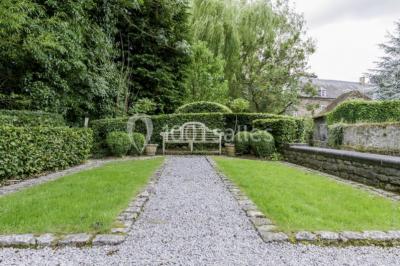 Chambre lumineuse avec deux lits simples, armoire ancienne, murs en bois et fenêtres donnant sur un jardin.
