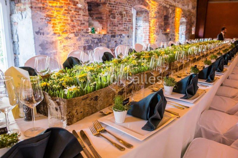 Table de banquet élégamment dressée avec des nappes blanches, des verres, des serviettes noires et une décoration florale…