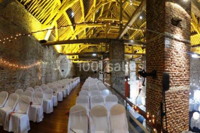 Chambre lumineuse avec deux lits simples, armoire ancienne, murs en bois et fenêtres donnant sur un jardin.