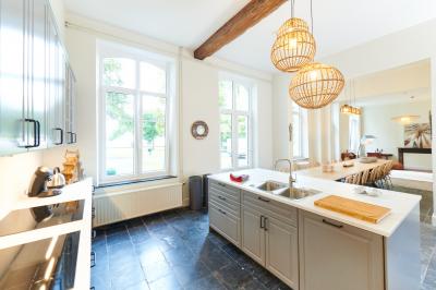 Chambre lumineuse avec deux lits simples, armoire ancienne, murs en bois et fenêtres donnant sur un jardin.