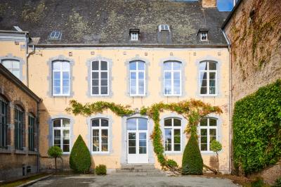 Chambre lumineuse avec deux lits simples, armoire ancienne, murs en bois et fenêtres donnant sur un jardin.