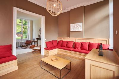Chambre lumineuse avec deux lits simples, armoire ancienne, murs en bois et fenêtres donnant sur un jardin.
