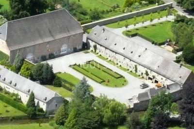 Chambre lumineuse avec deux lits simples, armoire ancienne, murs en bois et fenêtres donnant sur un jardin.