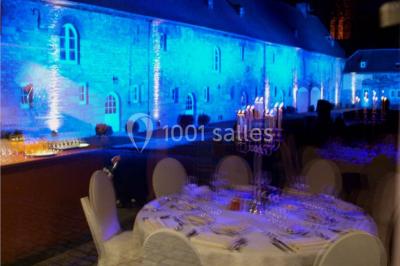 Chambre lumineuse avec deux lits simples, armoire ancienne, murs en bois et fenêtres donnant sur un jardin.
