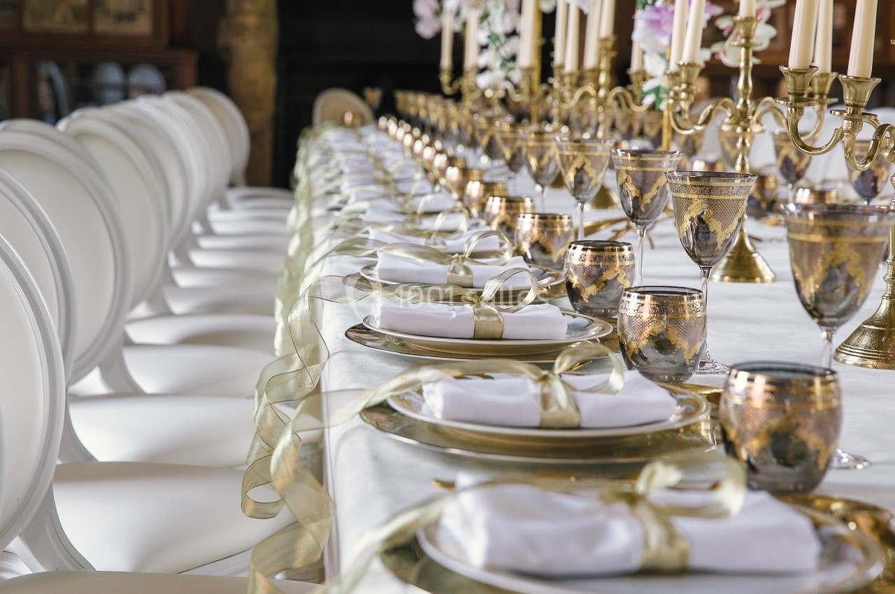 Table élégamment dressée avec des assiettes dorées, des verres assortis et des chandeliers, prête pour un dîner formel.