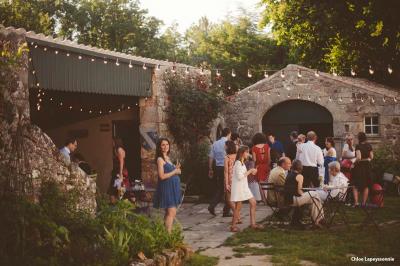Chambre lumineuse avec lit double, canapé, meubles en bois, plafond avec poutres bleues et fenêtre donnant sur l'extérieur.