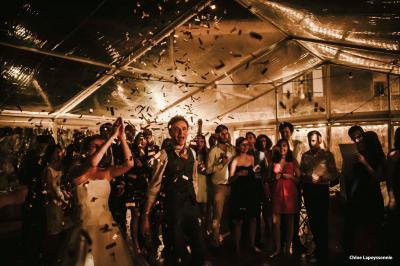 Chambre lumineuse avec lit double, canapé, meubles en bois, plafond avec poutres bleues et fenêtre donnant sur l'extérieur.