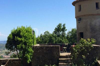 Chambre lumineuse avec lit double, canapé, meubles en bois, plafond avec poutres bleues et fenêtre donnant sur l'extérieur.