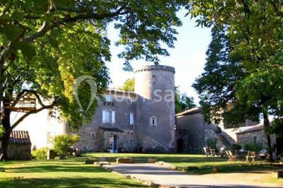 Chambre lumineuse avec lit double, canapé, meubles en bois, plafond avec poutres bleues et fenêtre donnant sur l'extérieur.