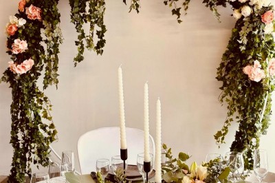 Table dressée avec une nappe blanche, chemin de table orange, décorations automnales et vaisselle élégante.