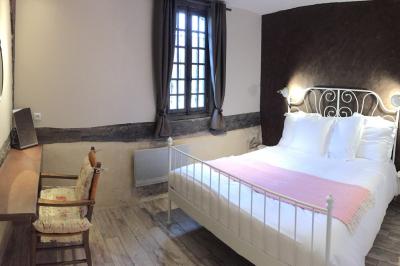 Salle de réception rustique avec poutres en bois apparentes, tables rondes dressées et chaises rouges.