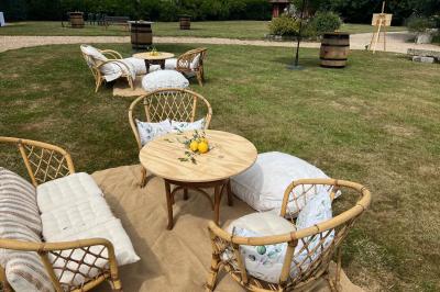 Salle de réception rustique avec poutres en bois apparentes, tables rondes dressées et chaises rouges.