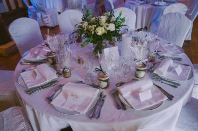 Salle de réception rustique avec poutres en bois apparentes, tables rondes dressées et chaises rouges.