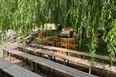 Salle de réception rustique avec poutres en bois apparentes, tables rondes dressées et chaises rouges.