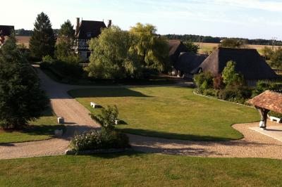 Salle de réception rustique avec poutres en bois apparentes, tables rondes dressées et chaises rouges.