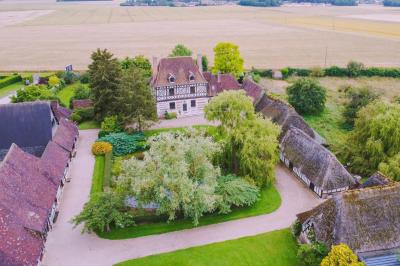 Salle de réception rustique avec poutres en bois apparentes, tables rondes dressées et chaises rouges.