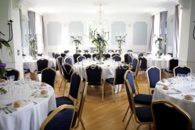 Maison en pierre et colombages entourée de verdure, avec toit en ardoise et fenêtres mansardées.
