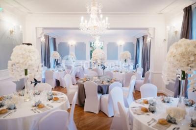 Maison en pierre et colombages entourée de verdure, avec toit en ardoise et fenêtres mansardées.