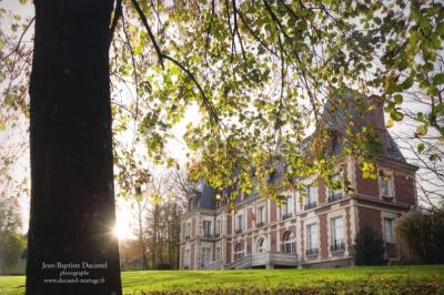 Maison en pierre et colombages entourée de verdure, avec toit en ardoise et fenêtres mansardées.