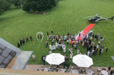 Maison en pierre et colombages entourée de verdure, avec toit en ardoise et fenêtres mansardées.