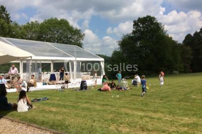 Maison en pierre et colombages entourée de verdure, avec toit en ardoise et fenêtres mansardées.