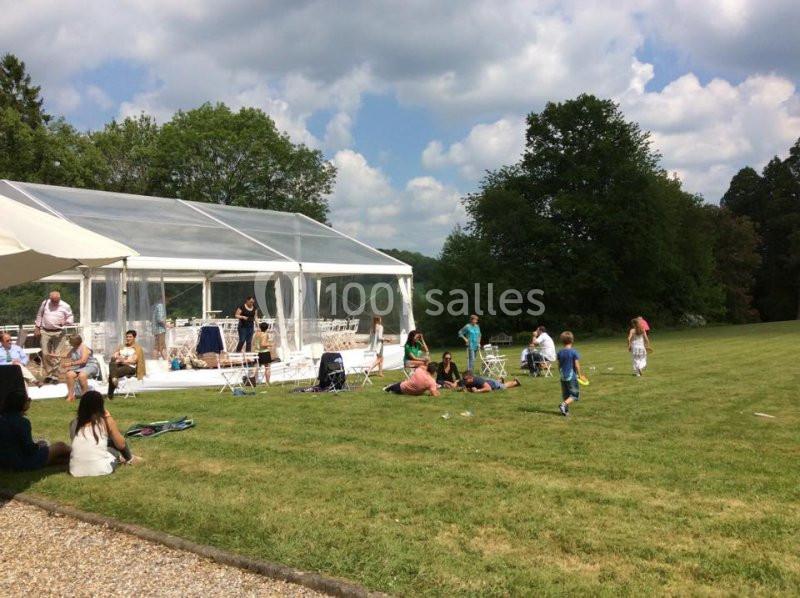 Des personnes profitent d'un espace extérieur avec une tente transparente installée sur une pelouse par temps ensoleillé.