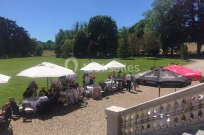 Maison en pierre et colombages entourée de verdure, avec toit en ardoise et fenêtres mansardées.
