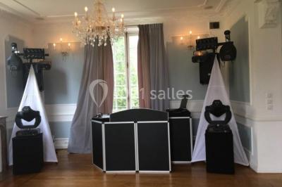 Maison en pierre et colombages entourée de verdure, avec toit en ardoise et fenêtres mansardées.