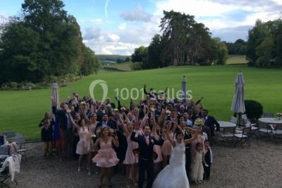 Maison en pierre et colombages entourée de verdure, avec toit en ardoise et fenêtres mansardées.