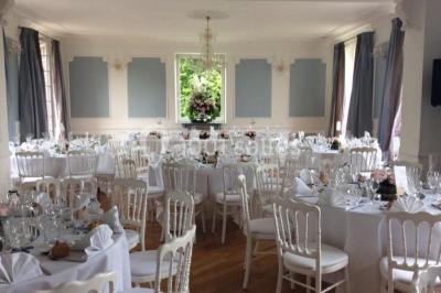 Maison en pierre et colombages entourée de verdure, avec toit en ardoise et fenêtres mansardées.