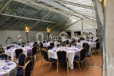 Maison en pierre et colombages entourée de verdure, avec toit en ardoise et fenêtres mansardées.