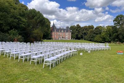 Maison en pierre et colombages entourée de verdure, avec toit en ardoise et fenêtres mansardées.